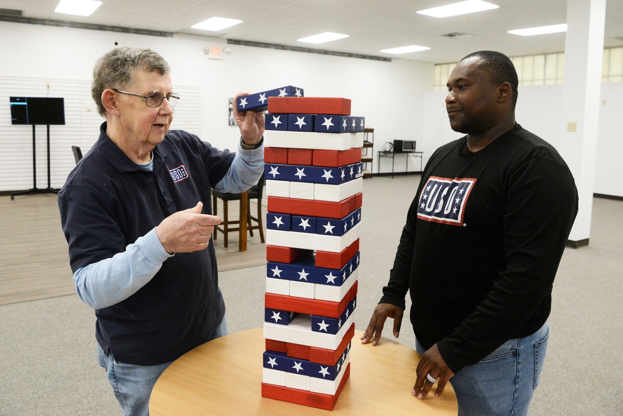 Patrick Arthur, left, USO New Jersey volunteer, and Jermaine Terry, USO New Jersey center operations specialist, demonstrate one of the many activities available to service members and their families at the new USO center at Joint Base McGuire-Dix-Lakehurst, N.J., April, 20, 2026. The 6,600-square-foot center features Wi-fi, computers, gaming systems, televisions, pool tables and enhanced lounge areas with refreshments, all at no cost to active duty, Reserve and National Guard service members, retirees and their dependents with valid identification. (U.S. Air Force photo by Kris Patterson)