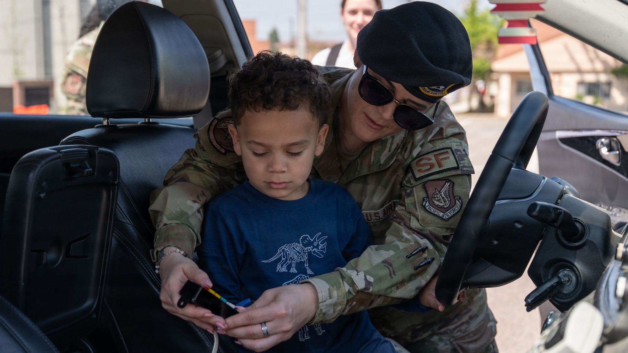 A U.S. Airman assigned to the 51st Security Forces Squadron demonstrates a patrol car function to a child during Police Week at Osan Air Base, Republic of Korea, May 5, 2026. Static displays provided Airmen and families an opportunity to learn about security forces equipment and capabilities. (U.S. Air Force photo by Senior Airman Rome Bowermaster)