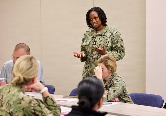 Cmdr. Christina Carter, director for public health assigned to Navy Medicine Readiness and Training Command Twentynine Palms, explains the goals of an influenza pandemic tabletop exercise as the event begins April 9, 2026. The discussion-based exercise evaluated the command’s emergency response procedures, Hospital Incident Command System activation, and operational readiness during a simulated H7N3 influenza pandemic scenario. (U.S. Navy photo by Christopher Jones, NMRTC / NH Twentynine Palms public affairs officer)