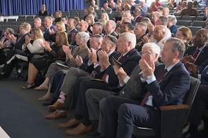 Several seated rows of audience members facing an off-camera stage in an auditorium.