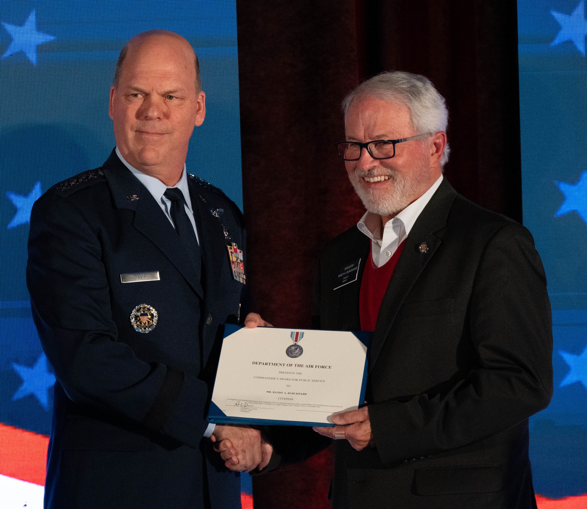 U.S. Air Force Gen. Stephen L. Davis presents the commander’s award for public service to North Dakota State Sen. Randy A. Burckhard.