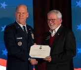 U.S. Air Force Gen. Stephen L. Davis presents the commander’s award for public service to North Dakota State Sen. Randy A. Burckhard.