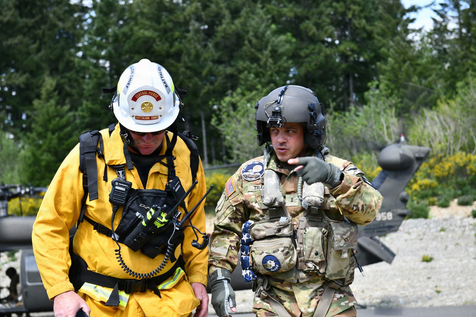 Chief Warrant Officer 3 Jarin Trakel, assigned to 1st Battalion, 168th General Support Aviation Battalion, Washington Army National Guard speaks with a firefighter from Central Pierce Fire and Rescue during water bucket training near Puyallup, Washington, May 7, 2026.