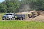 Dump trucks line up to be loaded with sand from a dredge material placement site.