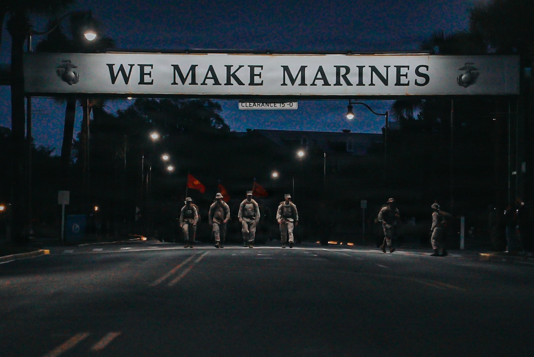 Recruits with Charlie Company, 1st Recruit Training Battalion, walk under the 'We Make Marines Sign' on Marine Corps Recruit Depot Parris Island, S.C., May 2, 2026. Following a culminating 15k hike to the parade deck, recruits are given their Eagle, Globe, and Anchor and officially become United States Marines. (U.S. Marine Corps photo by Cpl. Jordy Morales)