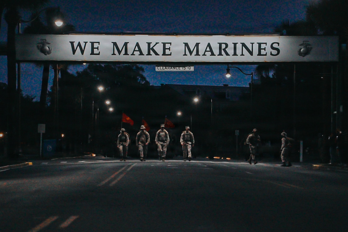 Recruits with Charlie Company, 1st Recruit Training Battalion, walk under the 'We Make Marines Sign' on Marine Corps Recruit Depot Parris Island, S.C., May 2, 2026. Following a culminating 15k hike to the parade deck, recruits are given their Eagle, Globe, and Anchor and officially become United States Marines. (U.S. Marine Corps photo by Cpl. Jordy Morales)