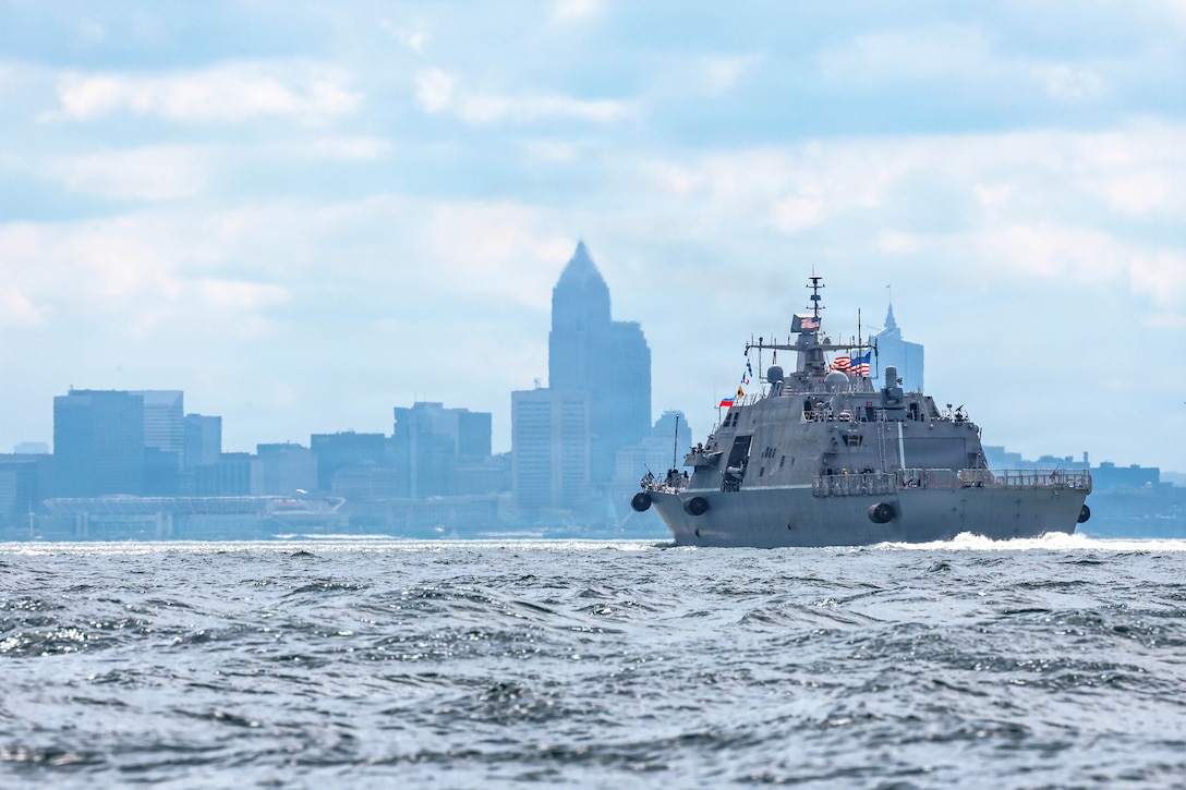 A ship transits a body of water toward a city's skyline.