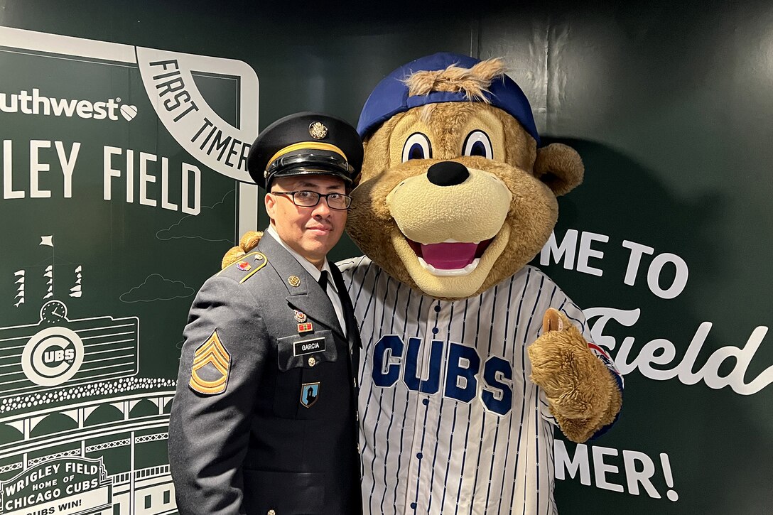 Sgt. 1st Class Moises Garcia, 85th U.S. Army Reserve Support Command, meets Clark, the Chicago Cubs’ mascot, after a military recognition during a Chicago Cubs MLB home game verses the Cincinnati Reds, May 5, 2026, at Wrigley Field.