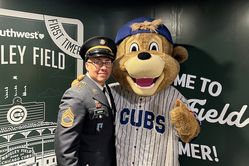Sgt. 1st Class Moises Garcia, 85th U.S. Army Reserve Support Command, meets Clark, the Chicago Cubs’ mascot, after a military recognition during a Chicago Cubs MLB home game verses the Cincinnati Reds, May 5, 2026, at Wrigley Field.