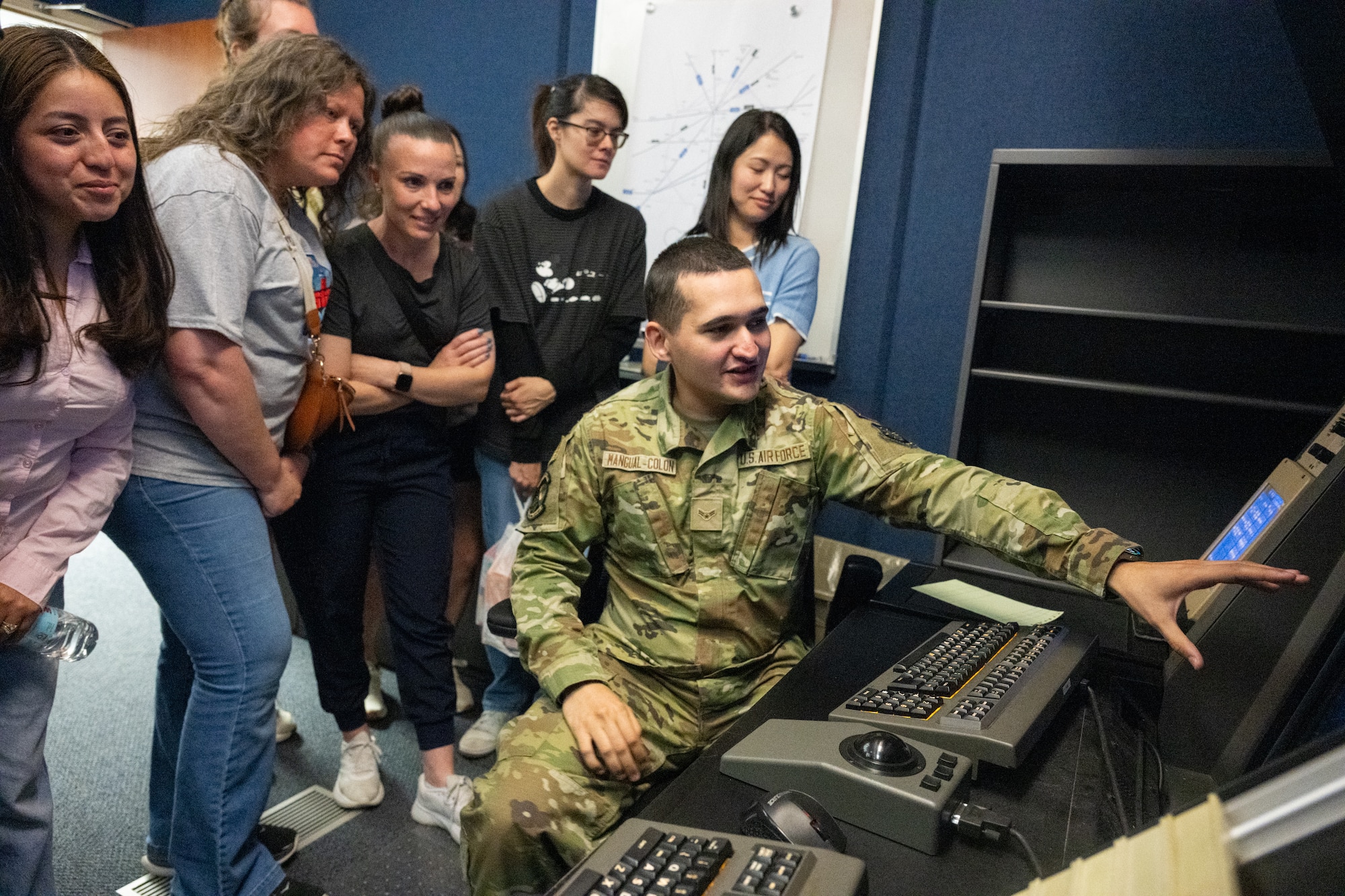 U.S. Air Force Airman 1st Class Christian Mangual-Colon, 436th Operations Support Squadron air traffic control apprentice, shows a group of military spouses a display screen showing aircraft in the surrounding airspace at Dover Air Force Base, Delaware, May 5, 2026. During the tour, the spouses got a chance to interact with Airmen at each location to familiarize themselves with their specific duties. (U.S. Air Force photo by Mauricio Campino)