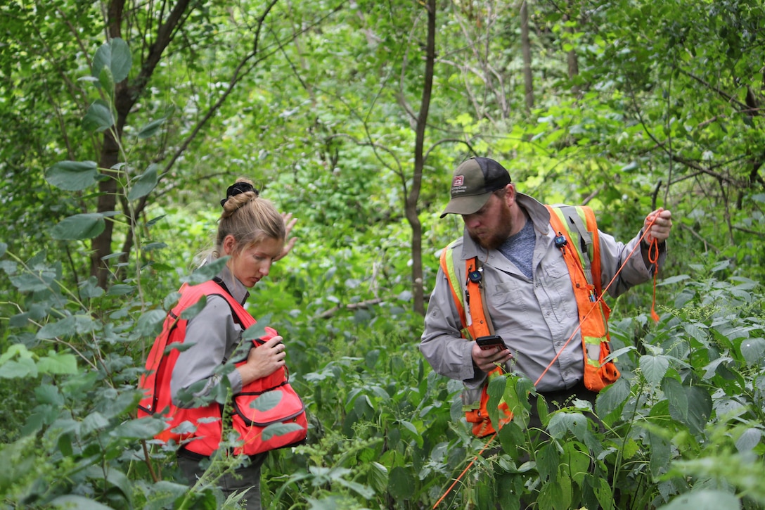 A man and a woman collect soil samples in the woods.