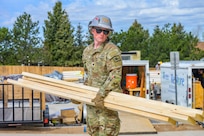 Interior electrician Spc. Derrick Dawson, assigned to Wyoming Army National Guard’s 307th Engineer Utilities Detachment, carries wooden planks during a two-week Innovative Readiness Training project providing military engineer training while helping construct homes for local residents in Cheyenne, Wyoming, May 9, 2026.