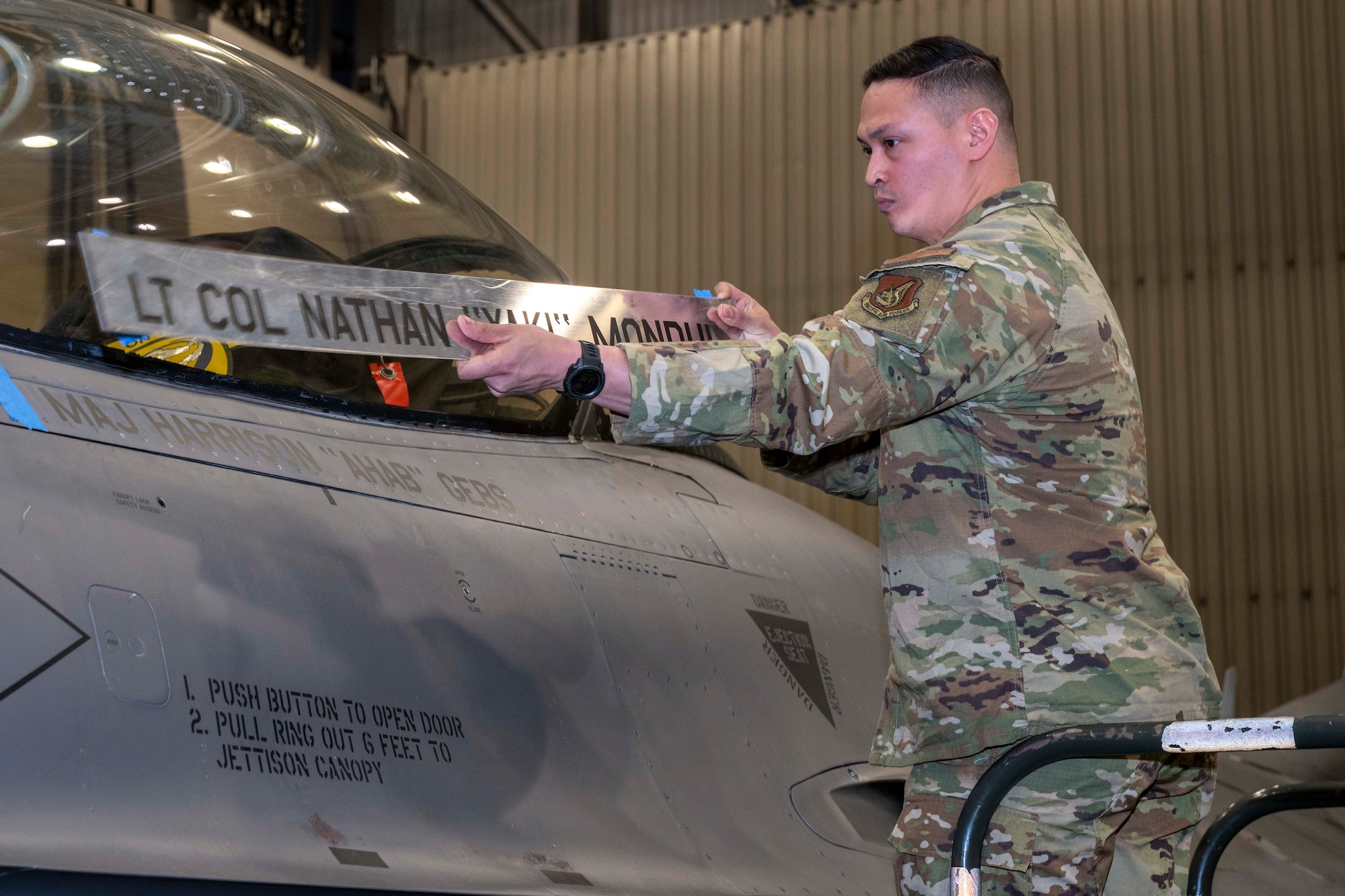 U.S. Air Force Senior Airman Daniel MaComber, 18th Fighter Generation Squadron F-16 Fighting Falcon dedicated crew chief, unveils the name of the new 18th Fighter Interceptor Squadron commander on an F-16 during a change of command ceremony at Eielson Air Force Base, Alaska, May 8, 2026.