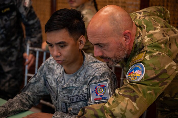 Philippine Air Force 2nd Lt. John Vincent M. Sarmiento, left, supervisor of cyber defense operations, and New Zealand Army Cpl. Matt Wakenell, network cyber analyst, exchange cyber defense tactics during a cyber defense exercise in support of Exercise Balikatan 2026 at Camp Gen. Emilio Aguinaldo, Manila, Philippines, April 28, 2026.