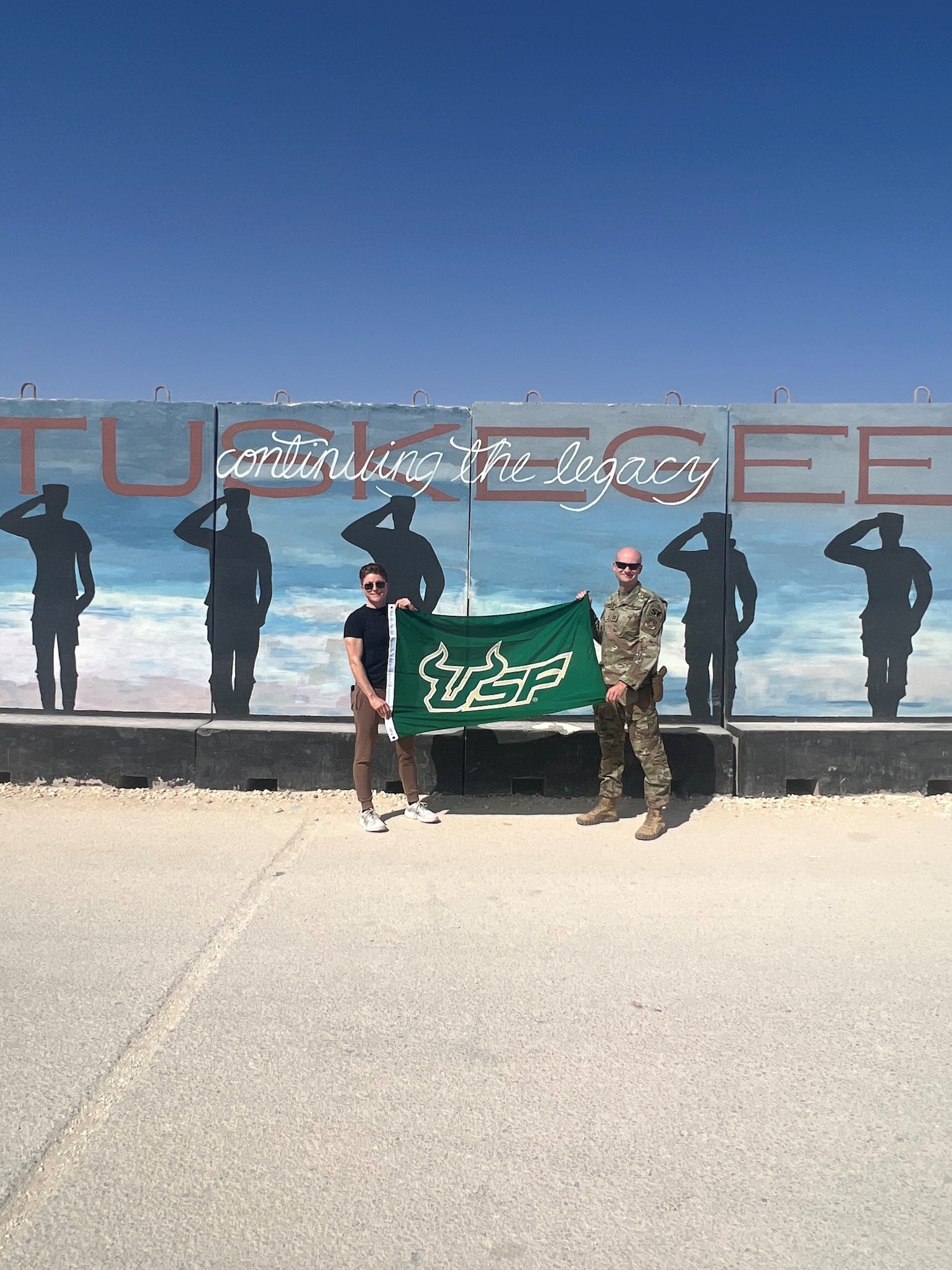 Capt. Michelle Strickland, left, and Capt. Alexander Johnson,  both graduates of the Air Force Reserve Officer Training Corps Detachment 158, pose with a University of South Florida flag in October 2023. Johnson credits staying connected with others, particularly with his AFROTC friends, for building his resilience and wingmanship throughout his career. (Courtesy photo)