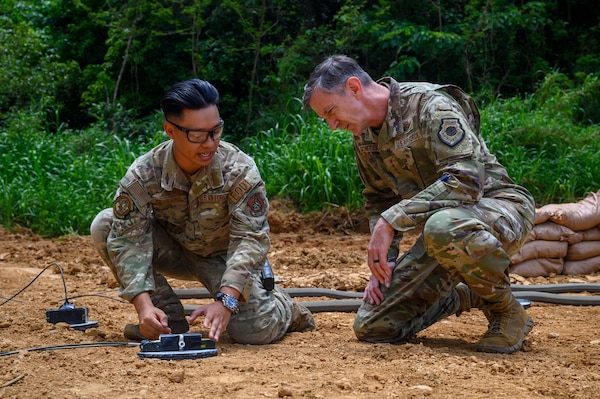 U.S. Air Force Gen. Kevin Schneider, right, Pacific Air Forces commander, observes Senior Airman Jack Reynard, 18th Civil Engineer Squadron explosive ordnance disposal journeyman, explain controlled detonation procedures at Kadena Air Base, Japan, April 29, 2026. The demonstration highlighted EOD capabilities supporting installation safety and mission effectiveness. (U.S. Air Force photo by Airman 1st Class Francisco Huerta)