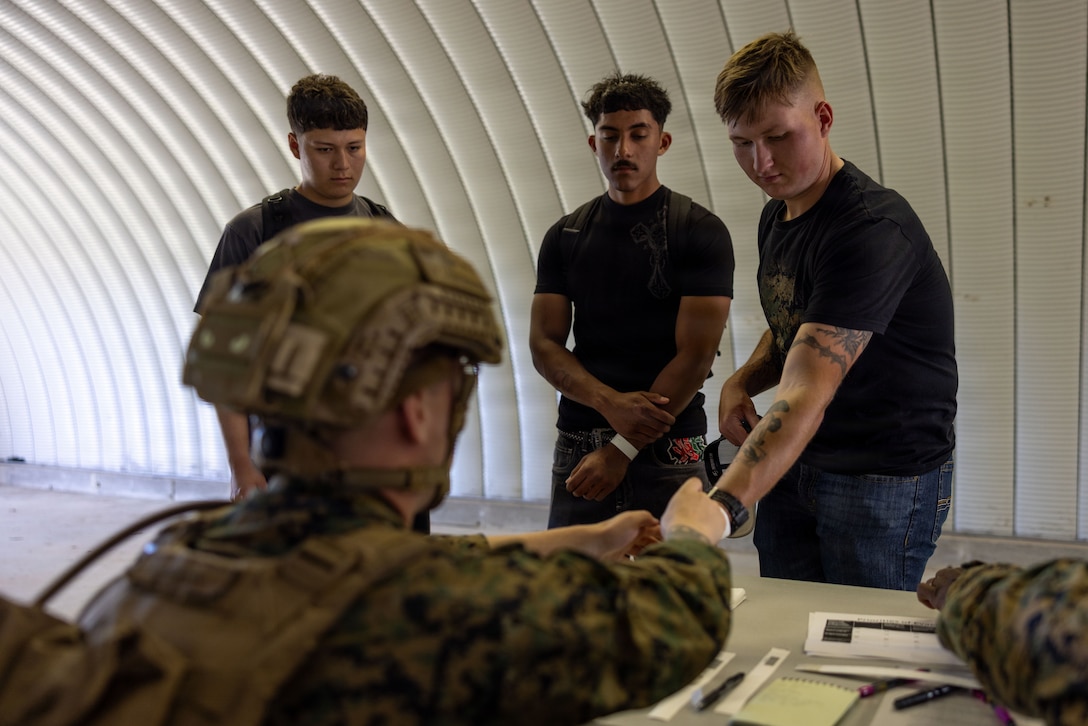 U.S. Marine Corps Cpl. Caleb Cannon, left, a motor vehicle operator with Combat Logistics Battalion 22, Combat Logistics Regiment 27, 2nd Marine Logistics Group, gives wristbands to role players at a simulated evacuation control center during a battalion field exercise at Marine Corps Auxiliary Landing Field Bogue, Bogue, North Carolina, May 6, 2026. CLB-22 conducted the battalion FEX to test the battalions combat readiness for the upcoming Marine Corps Combat Readiness Evaluation and set the conditions for successful integration as the Logistics Combat Element for the 26th Marine Expeditionary Unit. Canon is a native of North Carolina. (U.S. Marine Corps photo by Sgt. Rafael Brambila-Pelayo)