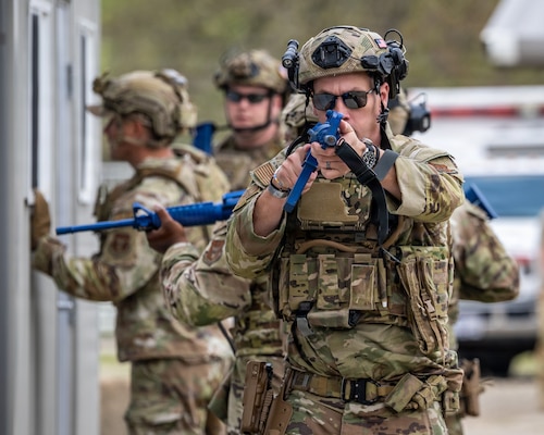 Security Forces member aims weapon
