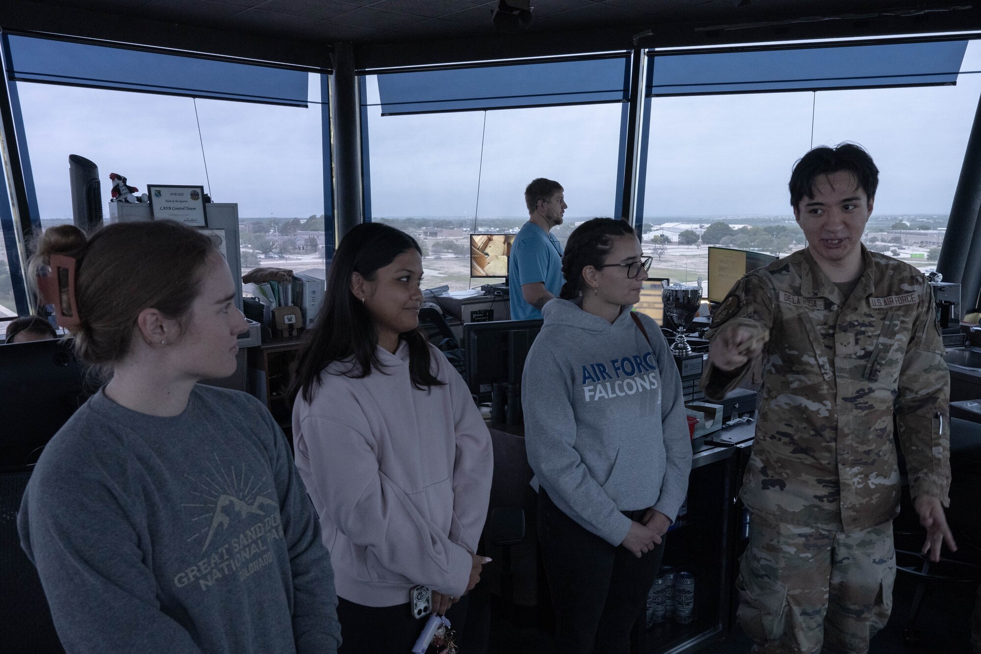 A trio of military spouses listens to U.S. Air Force Airman 1st Class Juan De La Rosa, 47th Operations Support Squadron air traffic control apprentice, during Military Spouse Appreciation Day at Laughlin Air Force Base, Texas, May 8, 2026. De La Rosa explained the daily operations of air traffic controllers to military spouses. (U.S. Air Force photo by Airman 1st Class Darryl Keith)
