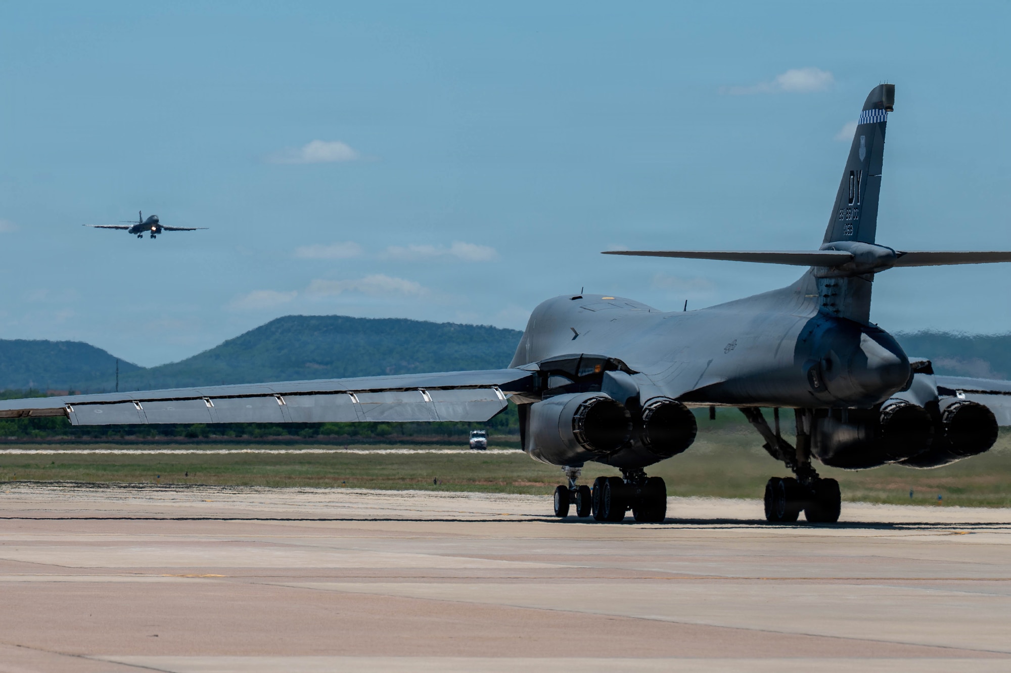 A U.S. Air Force B-1B Lancer assigned to the 7th Bomb Wing comes in for a landing as a 28th Bomb Squadron B-1B prepares for departure at Dyess Air Force Base, Texas, May 11, 2026. The arriving aircraft, tail 86-0117, returned to the fleet early following the completion of a preemptive replacement of its Forward Intermediate Fuselage at Wichita State University’s National Institute for Aviation Research. (U.S. Air Force photo by Airman 1st Class William Neal)