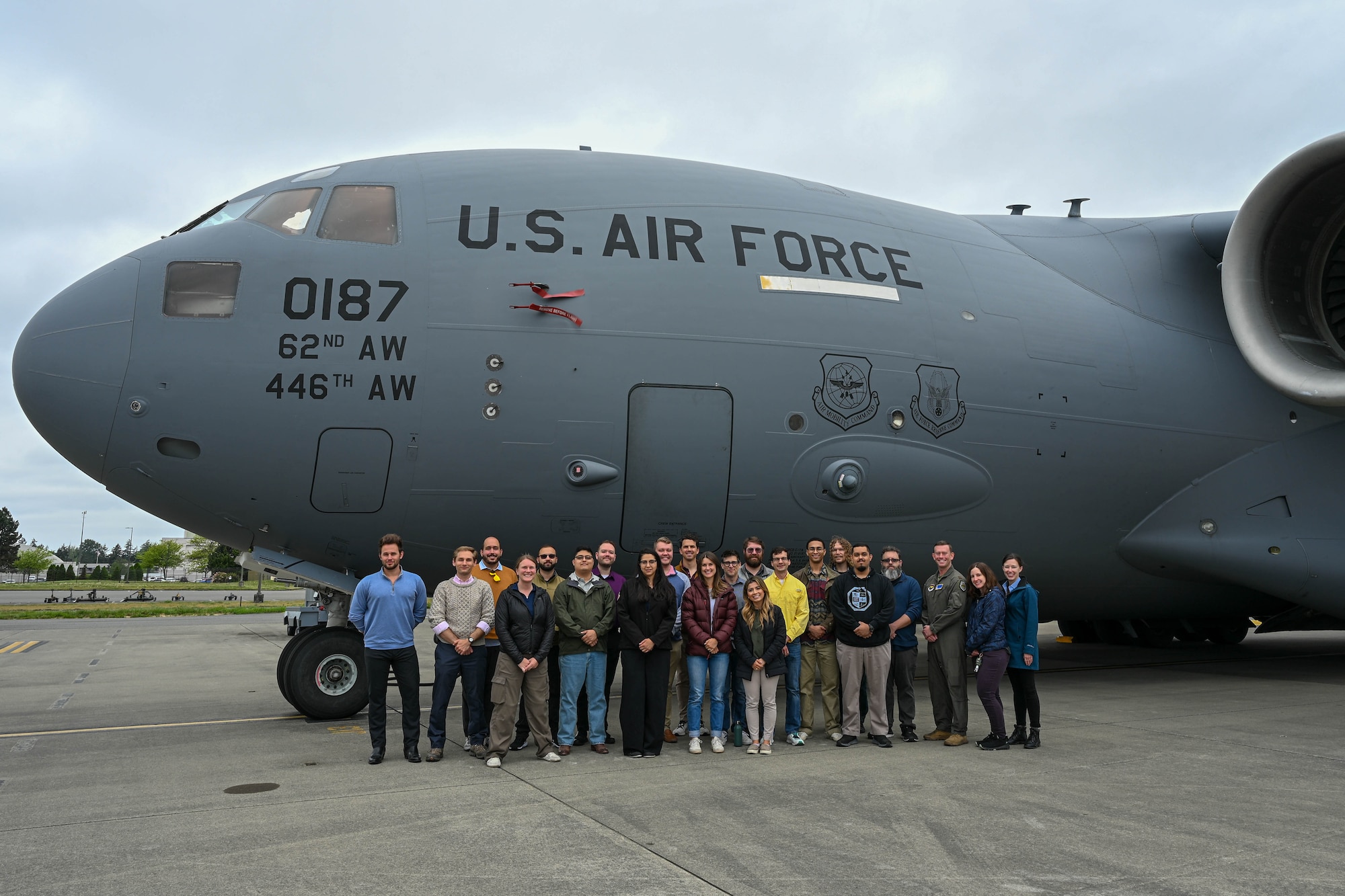 A group poses in front of a large aircraft.