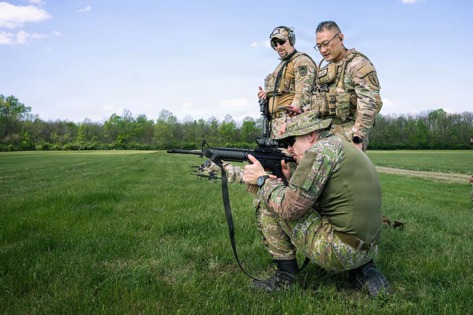 Indiana National Guard Master Sgt. Thuc Tran, center, the operations sergeant for Indiana's State Partnership Program, observes soldiers from the Slovak Armed Forces as they fire their M4 carbine at Camp Atterbury, near Edinburgh, Indiana, April 4, 2026.