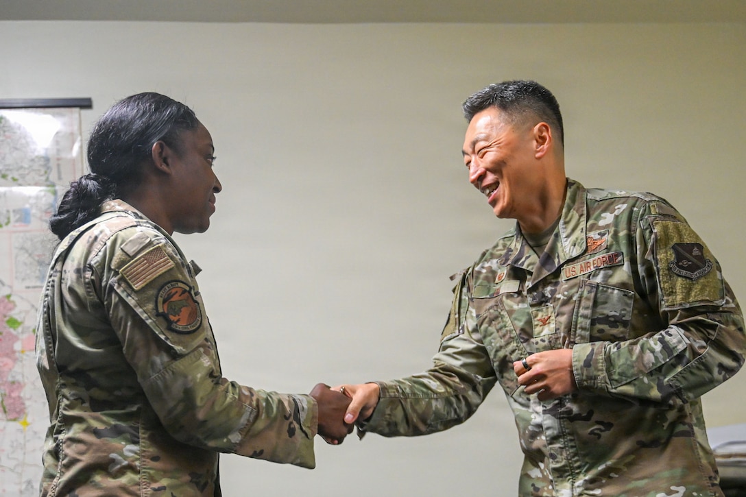 U.S. Air Force Col. Jun S. Oh, 316th Wing and installation commander, presents a commander’s coin to Senior Airman Sashakay T. Christie