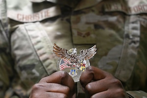 U.S. Air Force Senior Airman Sashakay T. Christe, an engineering assistant supervisor assigned to the 316th Civil Engineer Squadron, displays a commander's coin during a “Winnin’ Like a Griffin”