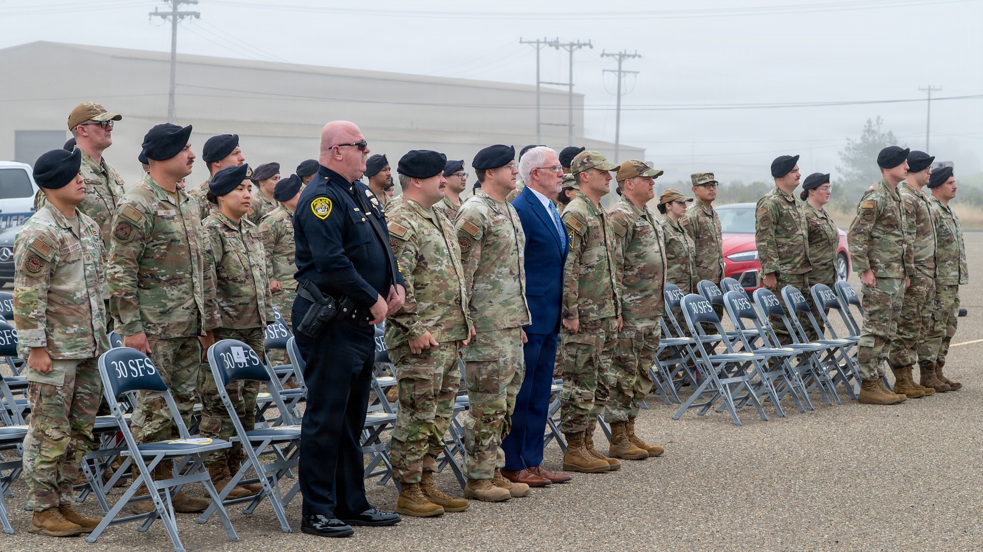 A group of servicemembers stand at attention for the posting of the colors.