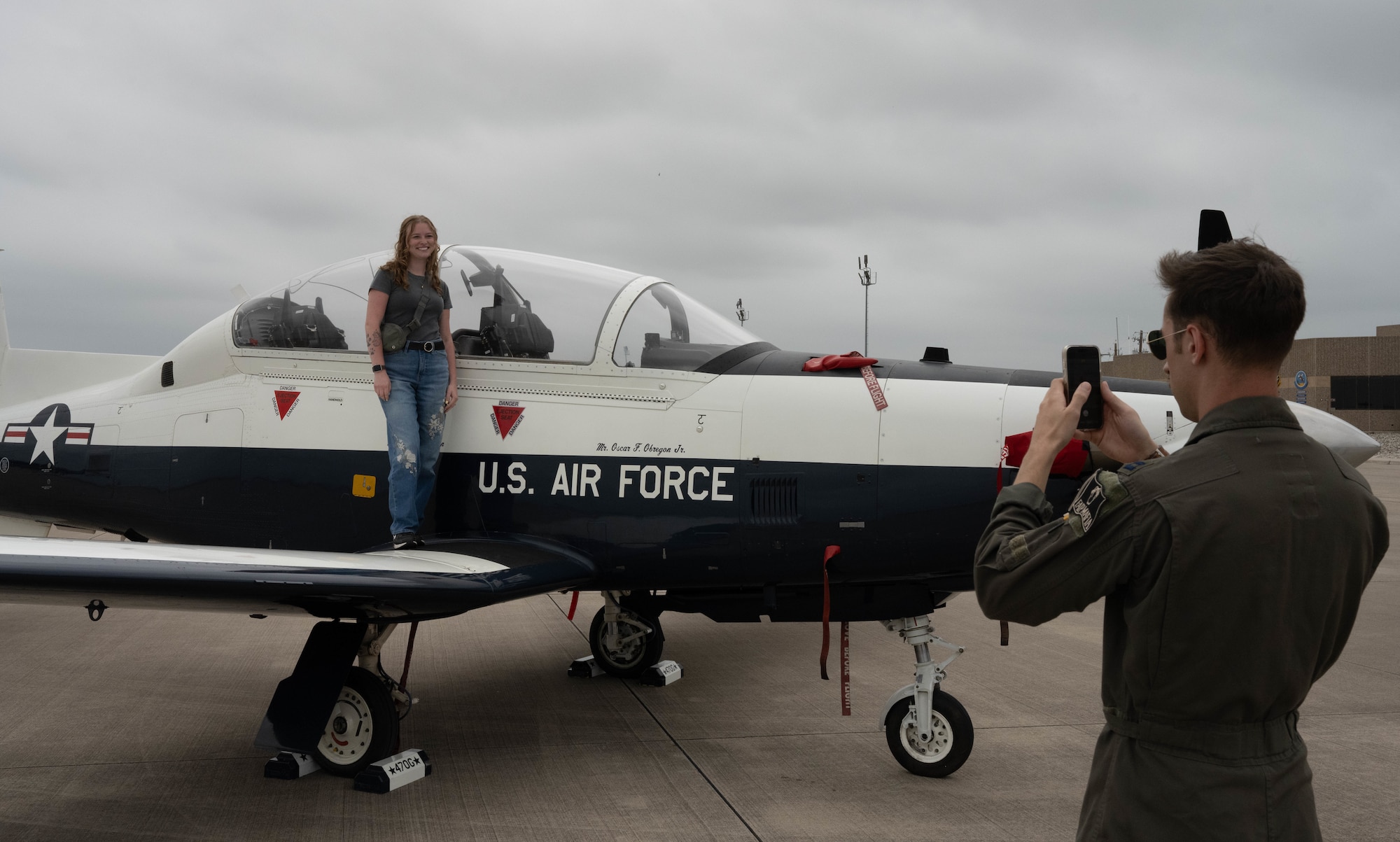 An instructor pilot assigned to the 47th Flying Training Wing takes a photo of a military spouse standing atop the wing of a T-6 Texan II during Military Spouse Appreciation Day at Laughlin Air Force Base, Texas, May 8, 2026. Military spouses and families were able to take photos next to a T-6 and T-38 Talon during the event. (U.S. Air Force photo by Airman 1st Class Darryl Keith)