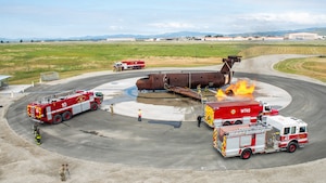 An overall for high atop a building of firefighters combating a simulated aircraft fire