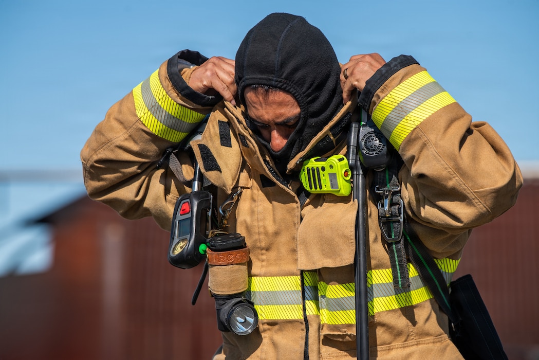 A firefighter dons his protective hood