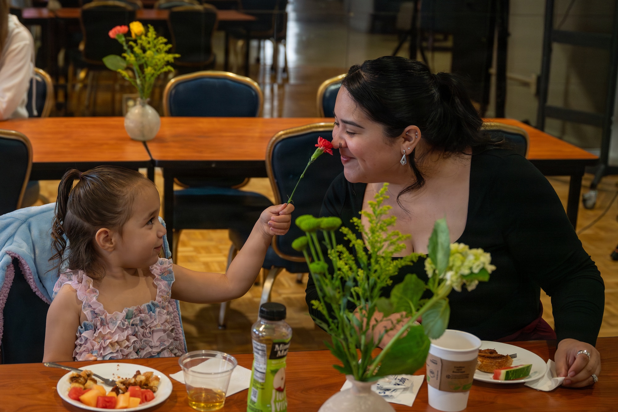A mom and her kid smell flowers.
