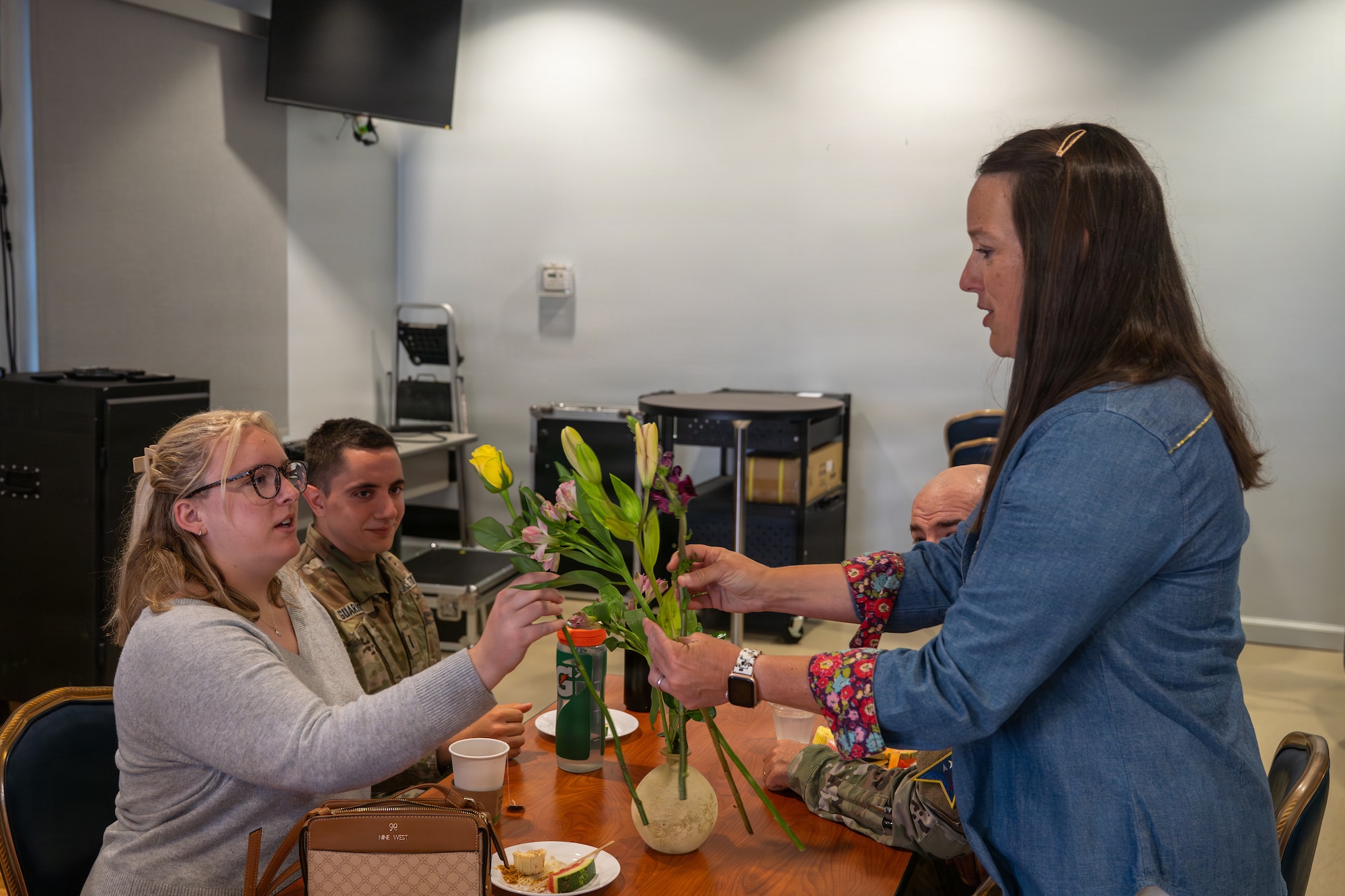 A person hands flowers to another person sitting at a table.