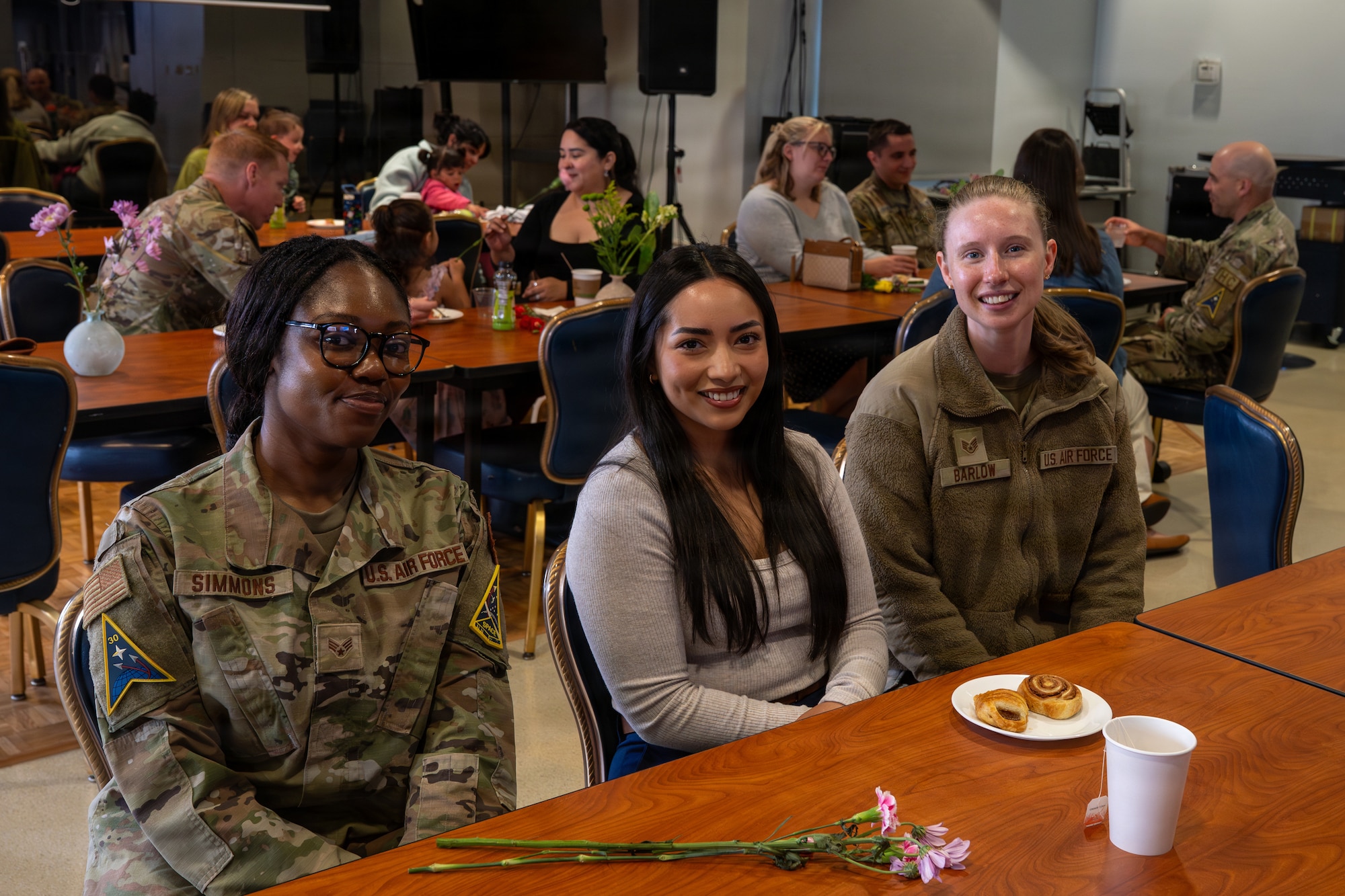 Three people sit at a table and smile at the camera.