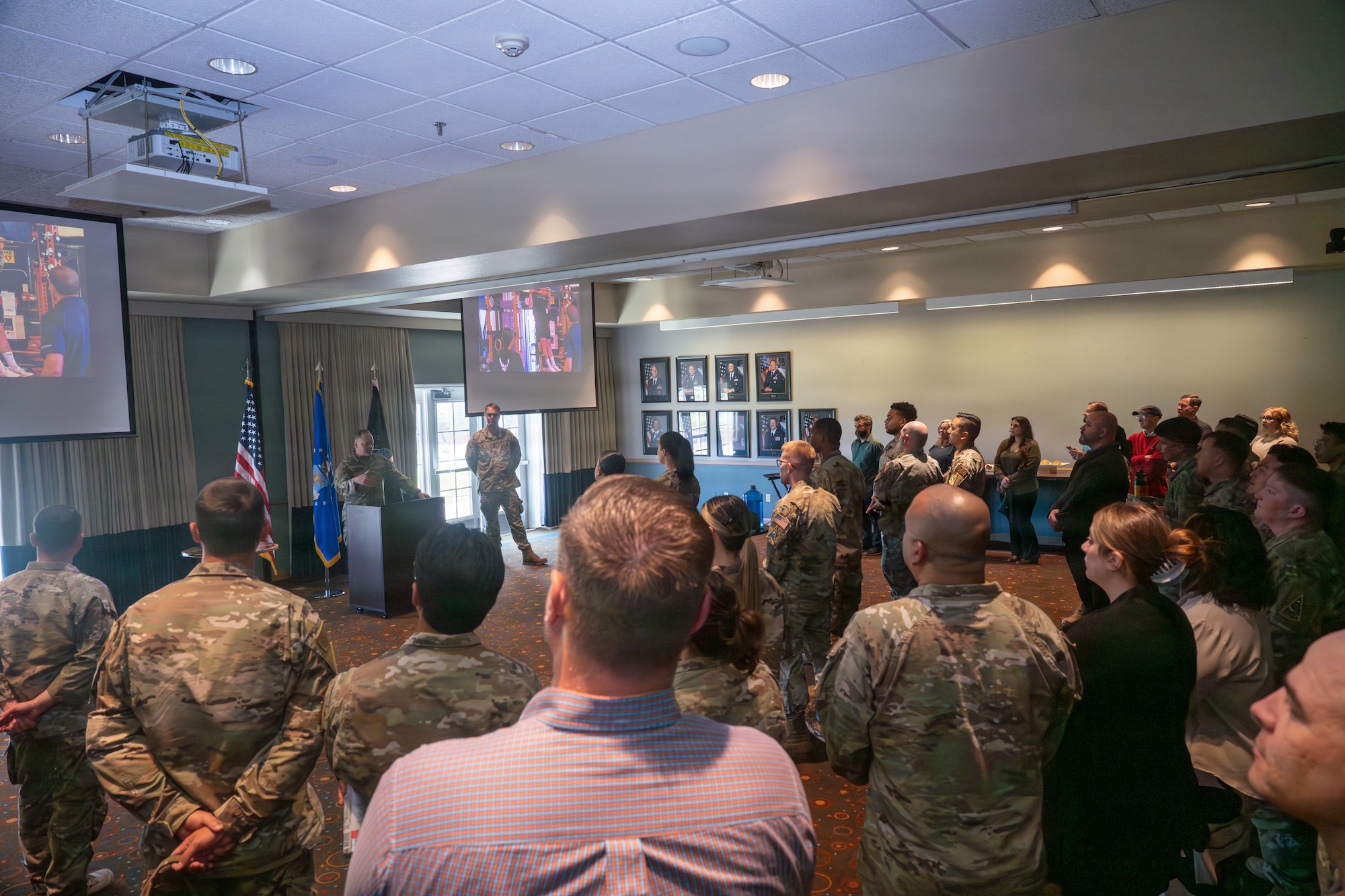 A crowd of people look at Colonel Horne as he stands and speaks to the crowd behind a podium.