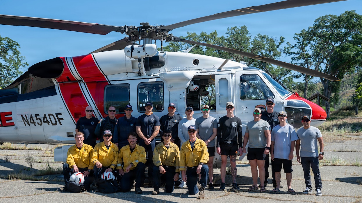 a group of people posing in front of a helicopter.