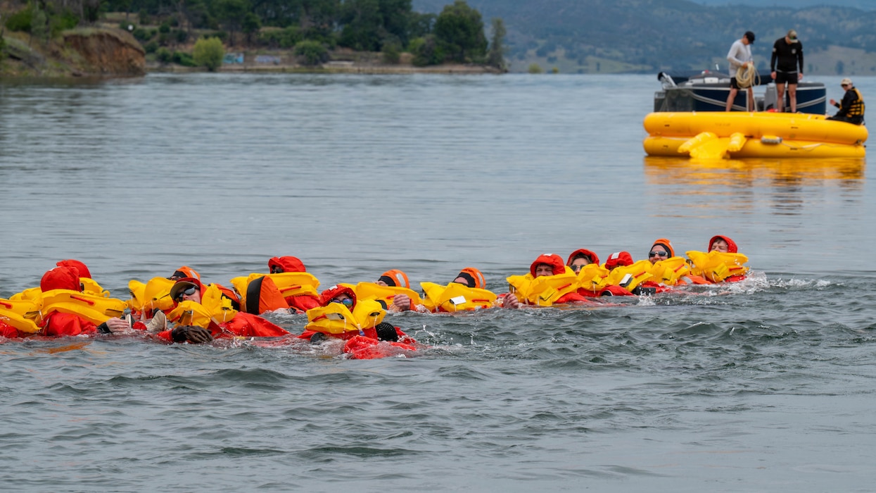 people floating in the water with a raft in the background