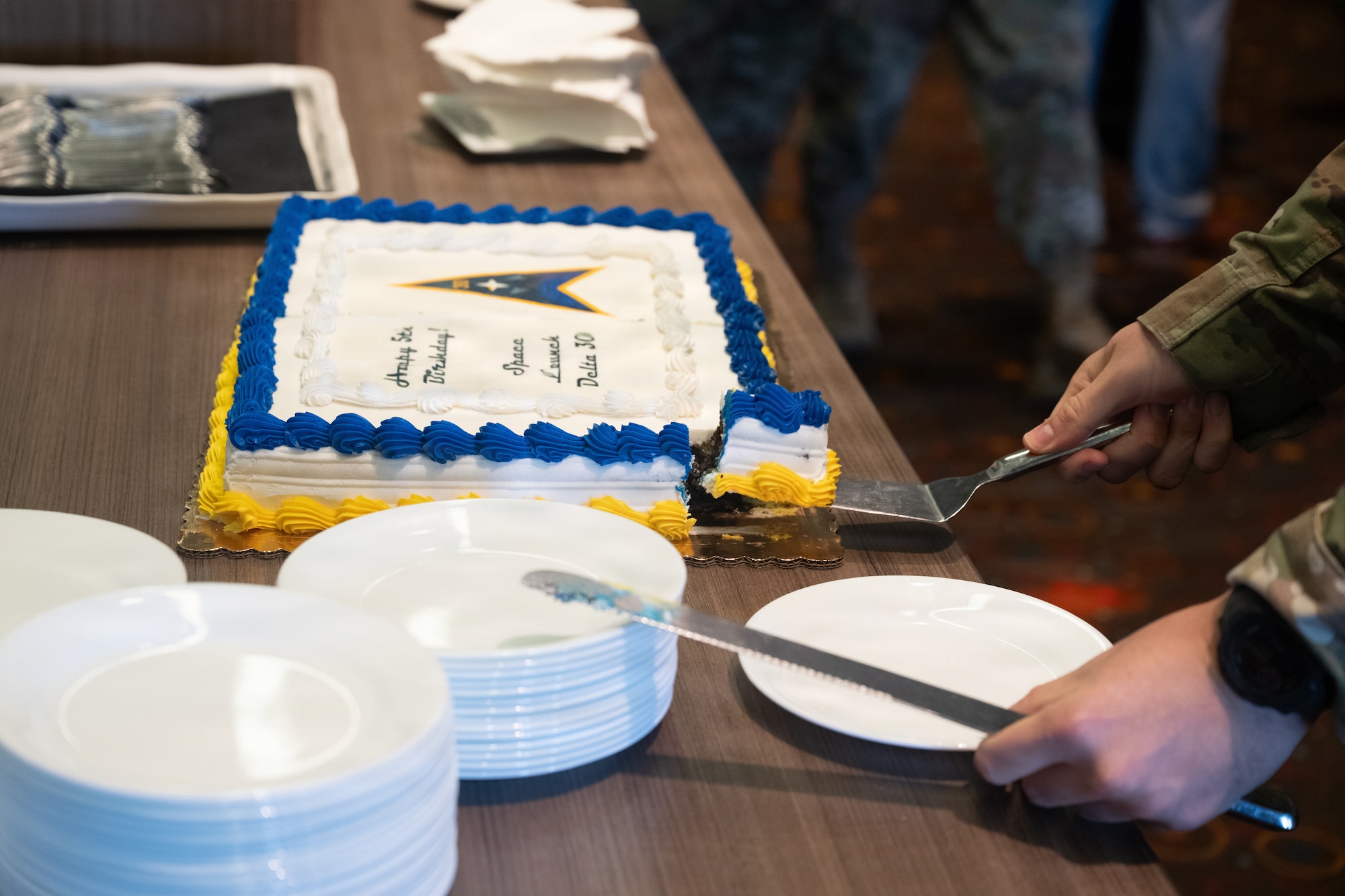 A person holds utensils near a cake.