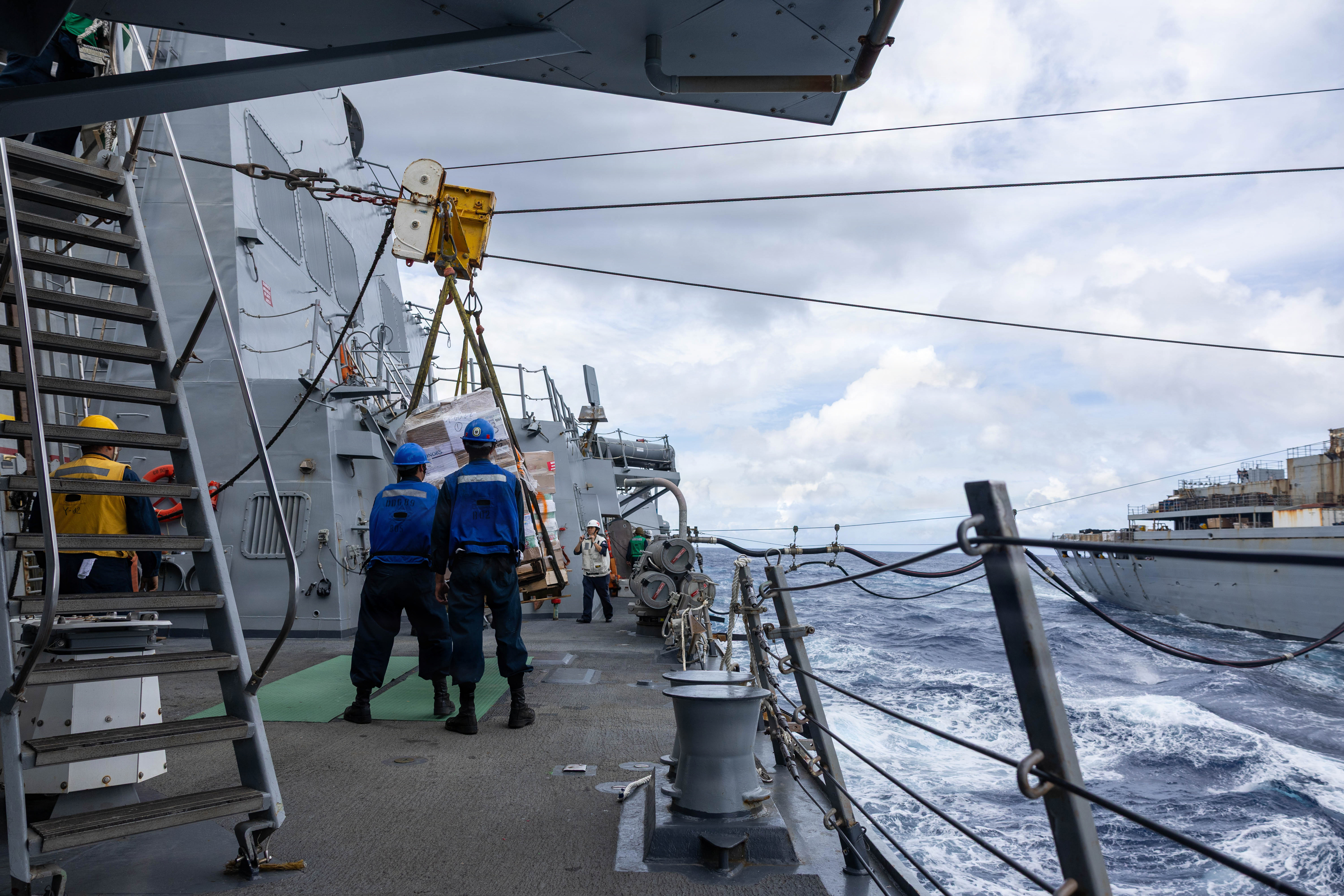 U.S. Navy Sailors lower supplies on the quarterdeck aboard Arleigh Burke-class guided-missile destroyer USS Mustin (DDG 89) during a replenishment-at-sea with Military Sealift Command Supply-class fast combat support ship USNS Arctic (T-AOE 8) in the Indian Ocean, May 10, 2026. Mustin is forward deployed and assigned to Destroyer Squadron (DESRON) 15, the Navy’s largest DESRON and U.S. 7th Fleet’s principal surface force. U.S. 7th Fleet, the Navy’s largest forward-deployed numbered fleet, routinely interacts and operates with allies and partners in preserving a free and open Indo-Pacific. (U.S. Navy photo by Mass Communication Specialist 2nd Class Timothy Dimal)