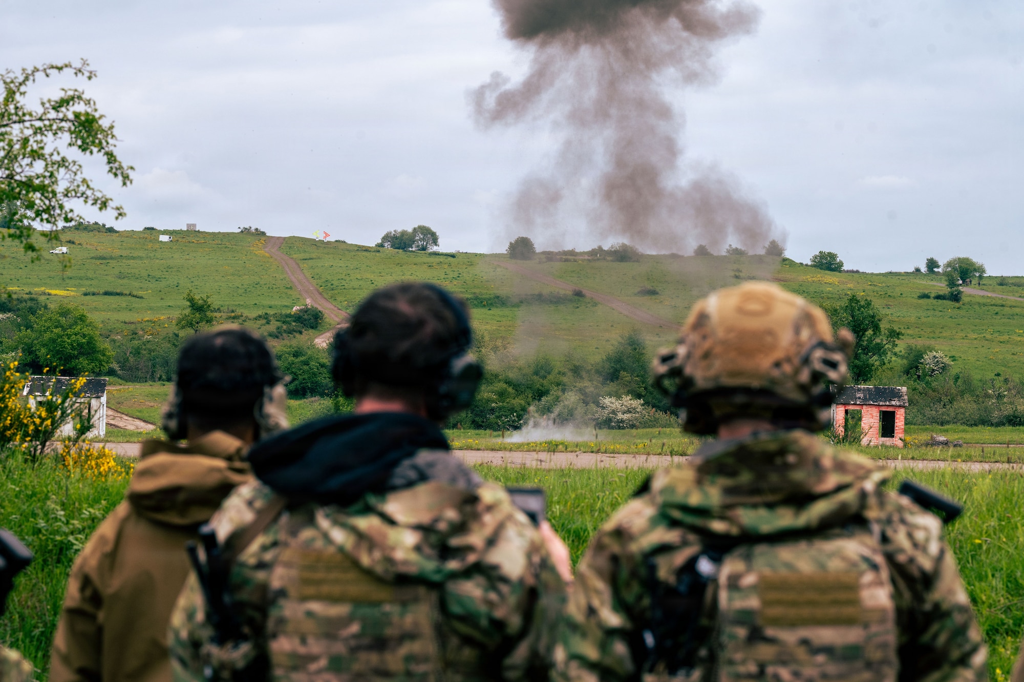 Allied and partner nation Explosive Ordnance Disposal technicians watch the controlled detonation of explosives