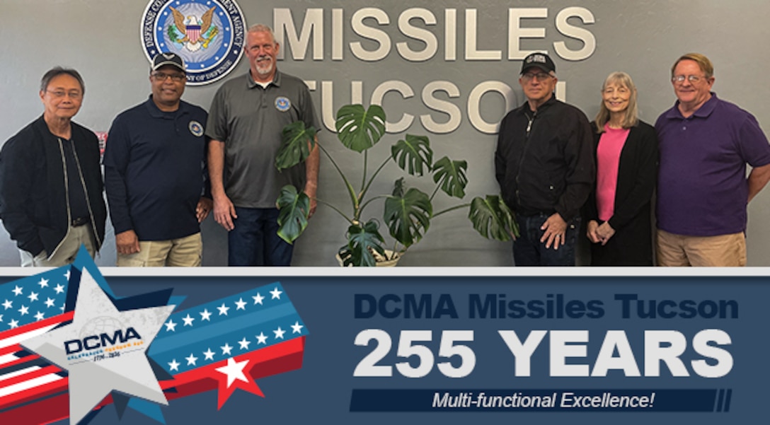 A group stands in an office lobby and poses for a picture