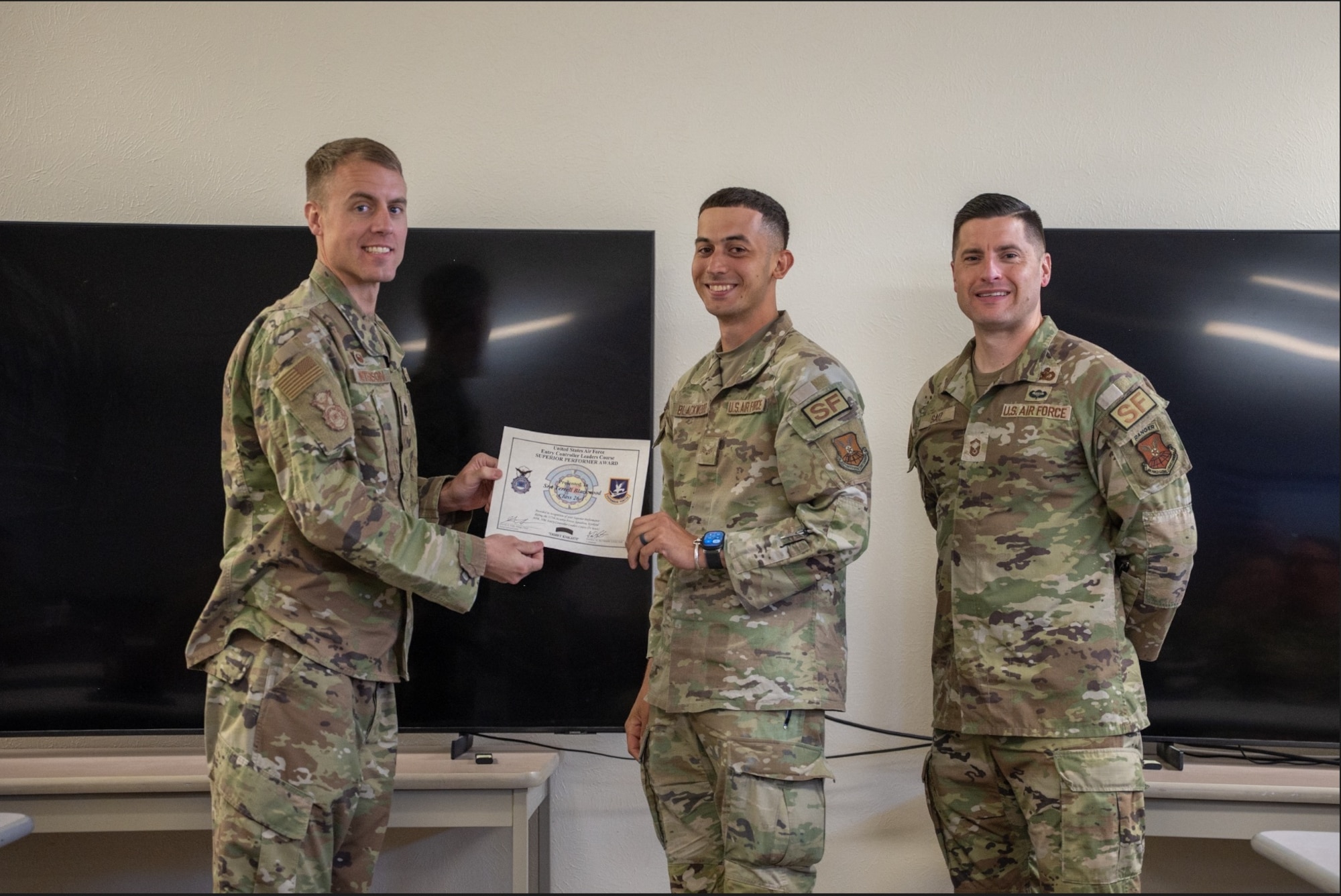 Lt. Col. Daniel Peterson, 377 Security Forces Squadron commander, left, and Senior MSgt. Gavin Saiz, 377 SFS senior enlisted leader, right, award Senior Airman Terrell Blackwood, 377 SFS defender, center, the Superior Performer Award certificate during the inaugural Entry Controller Leaders Course graduation ceremony at Kirtland Air Force Base, New Mexico, May 8, 2026. The professional development program prepares junior Defenders to lead installation entry control operations and respond to complex security scenarios including gate runners, bomb threats and hostile individuals. (U.S. Air Force photo by Senior Airman Donnell Schroeter)