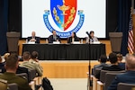 Speakers part of the "U.S. National Defense Strategy and its Implications for NATO and Europe" panel sit in front of a large screen with NDU's logo. From left to right: Dr. David Auerswald, Professor, National War College, NDU; Dr. Justin Anderson, Senior Fellow, INSS, NDU; Dr. Lisa A. Aronsson, Research Fellow, Institute for National Strategic Studies (INSS), NDU (Moderator); and Dr. Elena Pokalova, Professor, College of International Security Affairs (CISA).