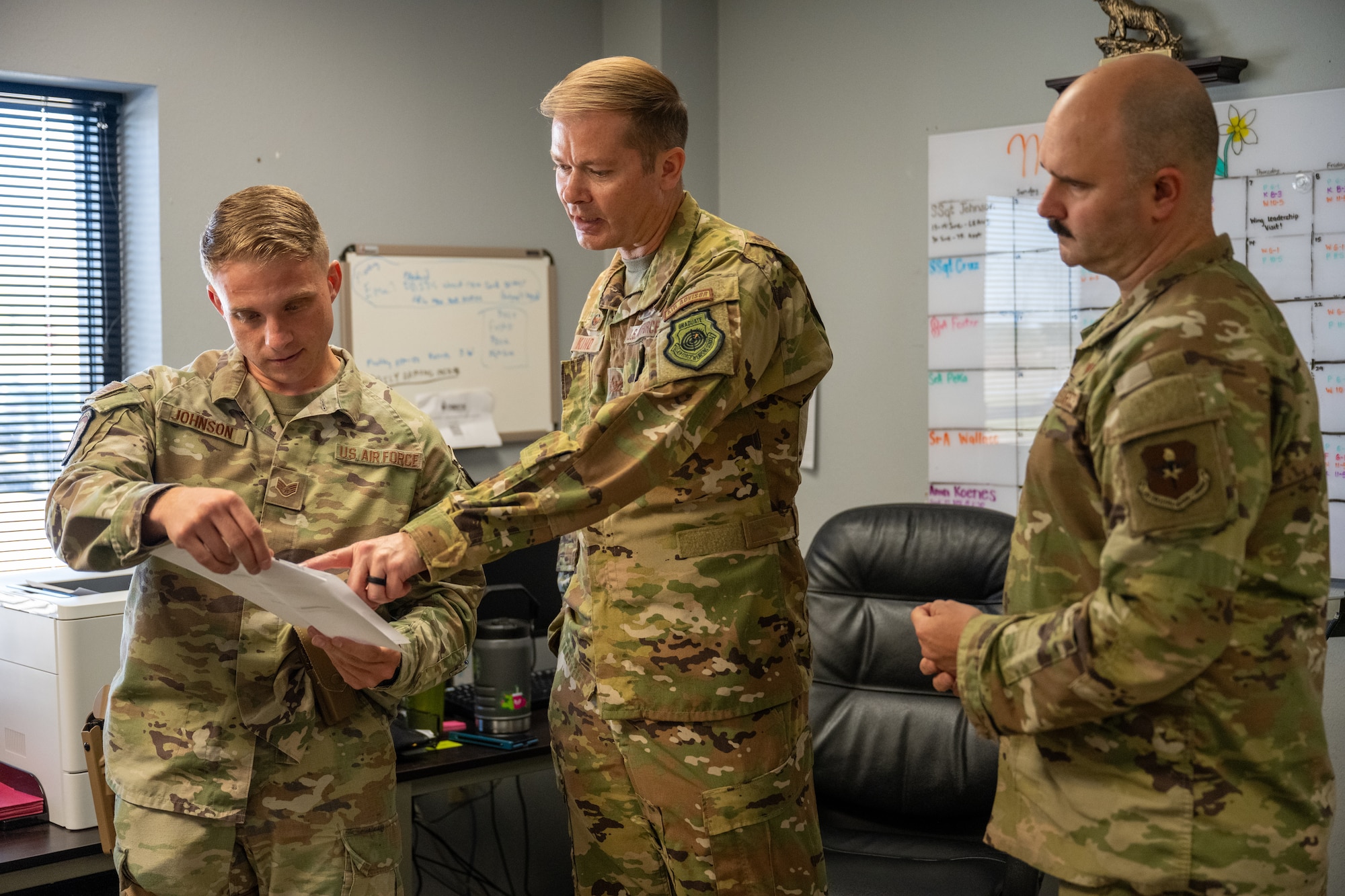 U.S. Air Force Col. Richard Kind, 97th Air Mobility Wing commander, center, Chief Master Sgt. Jonny Adams, 97th AMW command chief, right, and Staff Sgt. Brandon Johnson, 97th Security Forces Squadron visitor control center noncommissioned officer in charge, left, review visitor control center procedures at Altus Air Force Base, Oklahoma, May 7, 2026. The command team visited the visitor control center to learn how Defenders verify credentials, control installation access and support the security of the base. (U.S. Air Force photo by Airman 1st Class Nathan Langston)