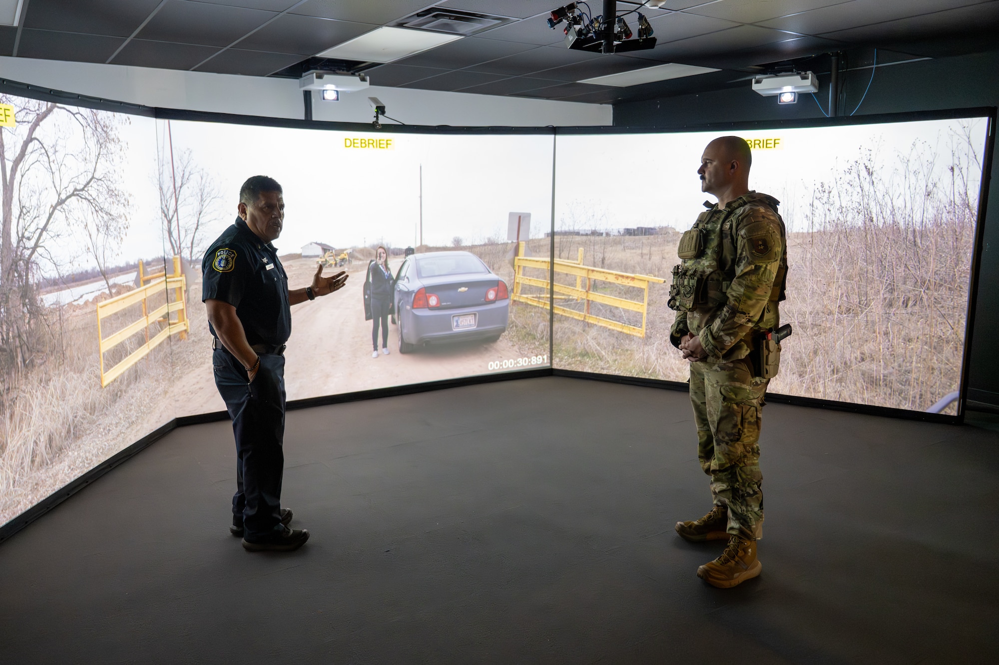 U.S. Air Force Chief Master Sgt. Jonny Adams, 97th Air Mobility Wing command chief, right, speaks with 2nd Lt. Frank Juarez, 97th Security Forces Squadron field training officer, left, during a Multiple Interactive Learning Objectives simulation system demonstration at Altus Air Force Base, Oklahoma, May 7, 2026. The MILO system uses interactive scenarios to help Defenders practice communication, decision-making and response procedures in a controlled training environment. (U.S. Air Force photo by Airman 1st Class Nathan Langston)