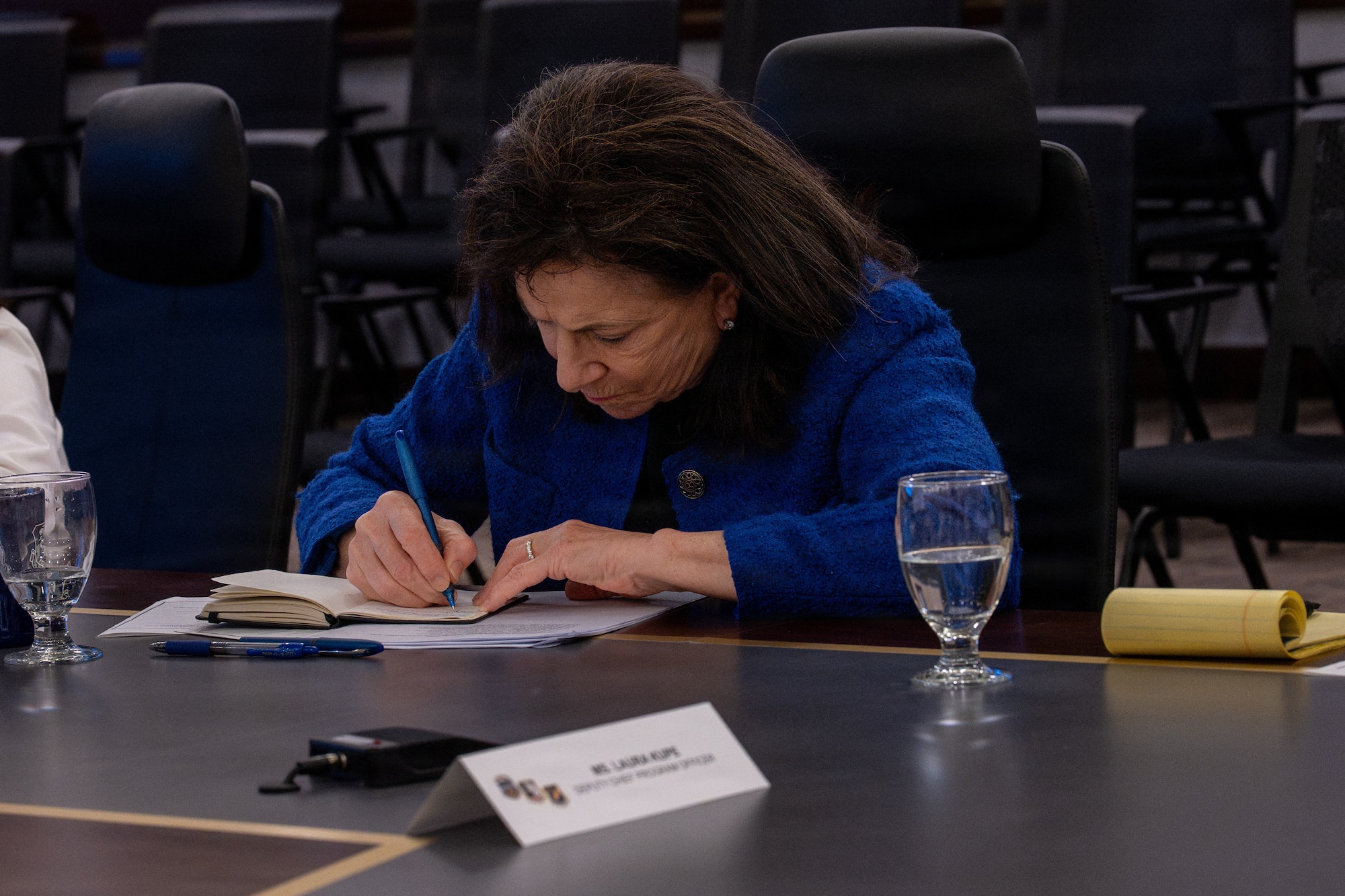 Laura Kupe, Business Executives for National Security, deputy chief program officer, writes notes at a briefing during an installation visit at the combined headquarters Alaskan NORAD Region, Alaskan Command, and Eleventh Air Force at Joint Base Elmendorf-Richardson, Alaska, May 4, 2026. The briefing helped Kupe and her team better understand and discuss the important missions of the combined headquarters, and discussed homeland defense, operations at JBER and challenges unique to the arctic environment. (U.S. Air Force photo by Senior Airman Tala Hunt)