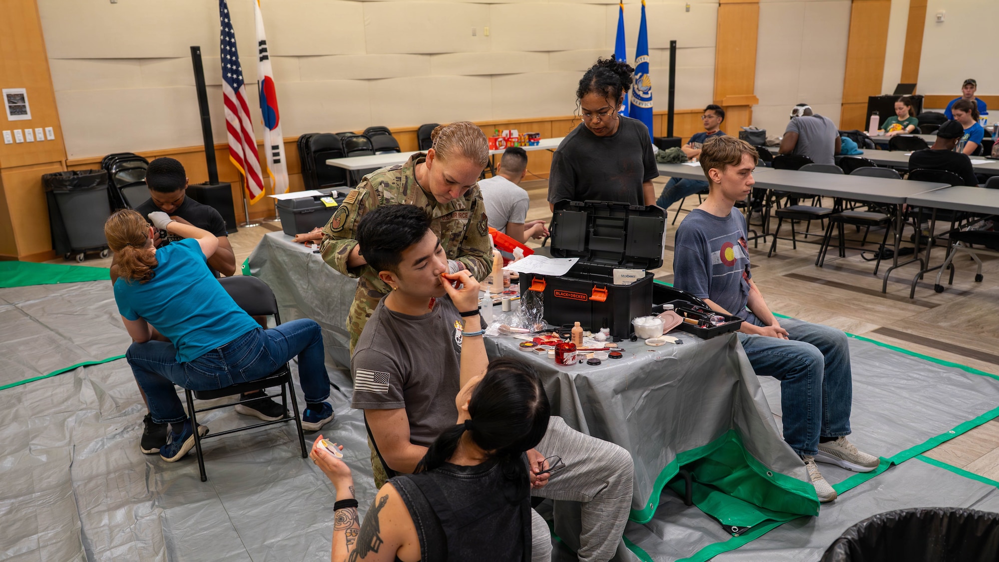 U.S. Air Force personnel apply moulage makeup to participants before an active shooter scenario during exercise Mustang Rodeo 26-2 at Osan Air Base, Republic of Korea, May 12, 2026. Mustang Rodeo 26-2 provides regular opportunities for Airmen to rehearse targeted skill sets and ensures that critical tasks are performed with speed and precision, even when operating under limited time or simulated operational stress. (U.S. Air Force photo by Airman 1st Class Megan Cusmano)