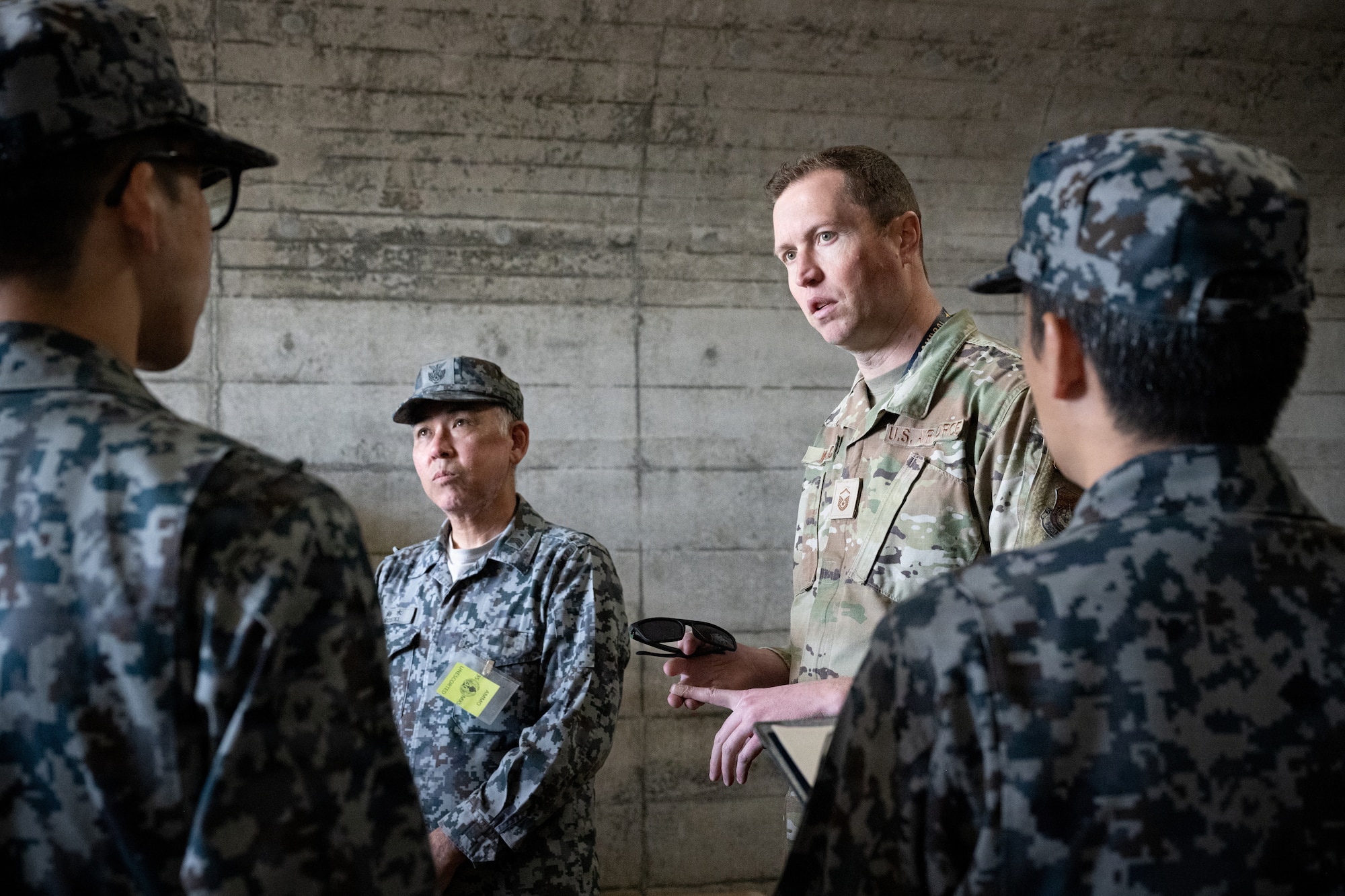 U.S. Air Force Master Sgt. Andrew Waldo, 35th Munitions Squadron precision guided munitions production superintendent, briefs Japan Air Self-Defense Force airmen (JASDF) on munitions storage igloos during an immersion tour.