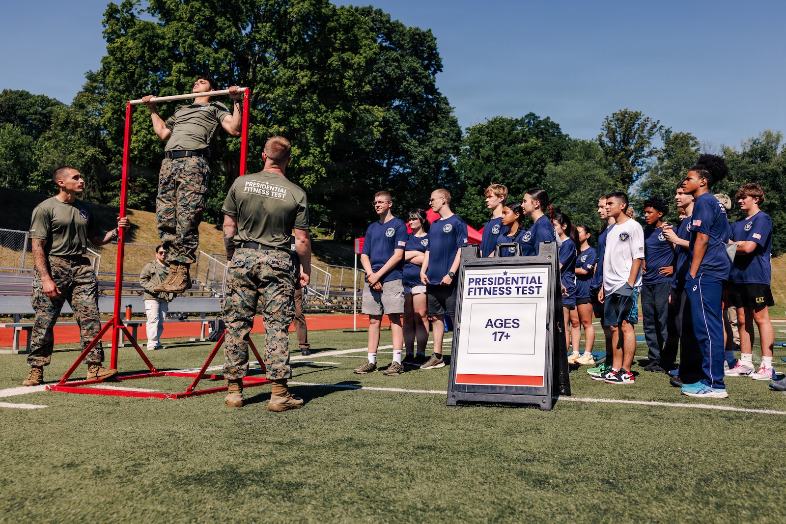U.S. Marines with Marine Corps Base Quantico demonstrate pull-ups to students from MCB Quantico’s Department of War Education Activity schools prior to conducting the Presidential Fitness Test at Butler Stadium on MCB Quantico, Virginia, May 12, 2026. The Presidential Fitness Test consists of three fitness components that are designed to strengthen health, physical fitness, resilience, and establish lifelong healthy habits. The PFT also recognizes multiple levels of achievements, including the Presidential Fitness Award, National Fitness Award, Completion recognition and improvement.  (U.S. Marine Corps photo by Cpl. Braydon Rogers)